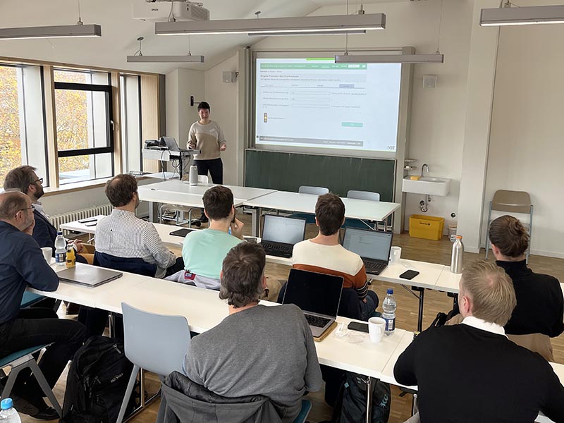 Seminarraum: Person präsentiert Folien vor Beamer.