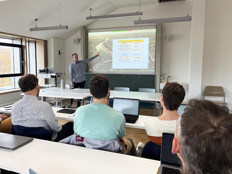 Person präsentiert Folien an Beamer vor Workshop-Teilnehmenden.